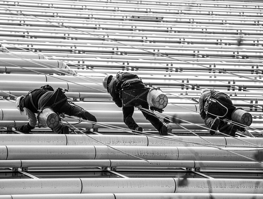 Rope-access workers climbing a ribbed building facade