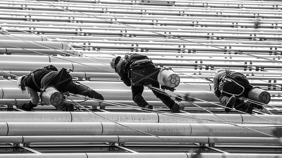 Rope-access workers climbing a ribbed building facade
